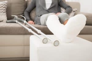 Woman With Plastered Leg Sitting On Couch