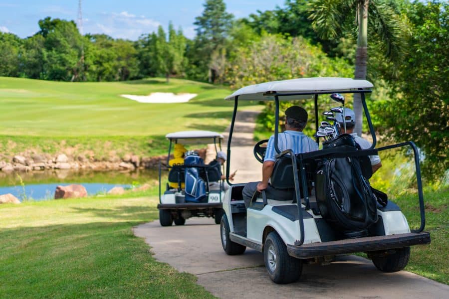 Golfer driving golf cart on golf course in summer sunny day