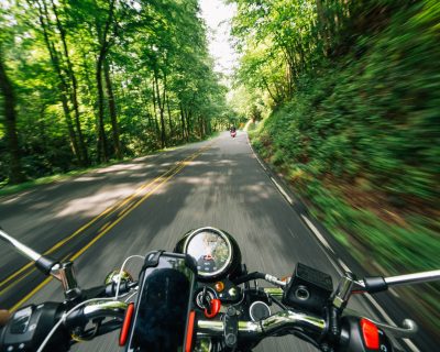 Photo of Person Riding Motorcycle on Road Between Trees