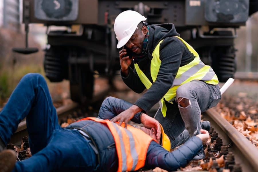 Railroad engineer injured in an accident at work on the railway tracks, coworker calling for help