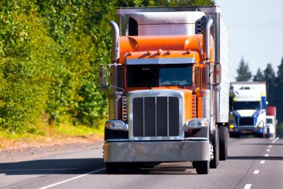 Classic orange semi truck reefer trailer on highway