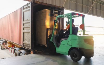 Forklift driver loading goods pallet into a truck trailer