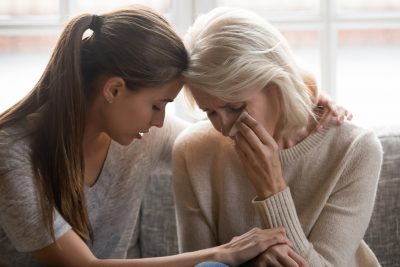 Grownup daughter soothes aged mother, holds her hand feeling empathy