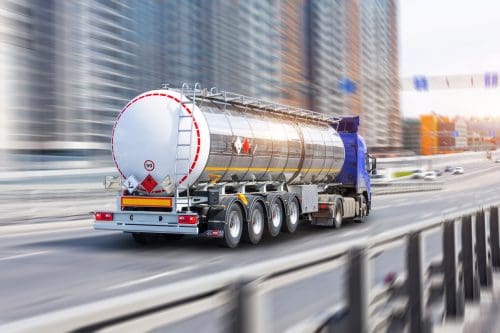 Heavy gas truck with a chrome metal cistern rushing along the street