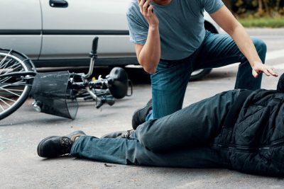 Man calling an ambulance for a victim of a car and bicycle crash