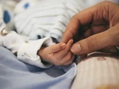Mother holding the hands of a new born baby