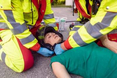 Paramedics removing helmet of injured motorcyclist after an accident