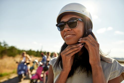 Smiling young african american girl putting on helmet