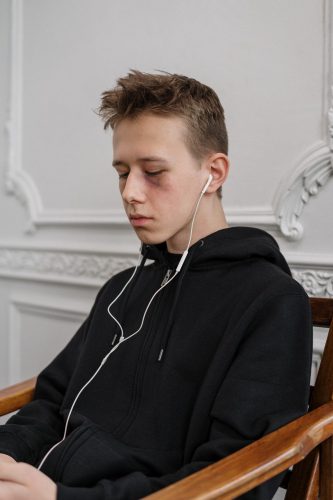 Teenage boy with a black eye listening to earbuds