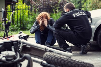 Terrified victim of a traffic collision of motorcycle with a car and policeman