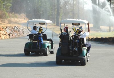 Two golf carts being driven on golf cart path