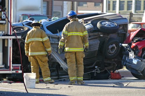 Two firefighters investigating wrecked car on its side