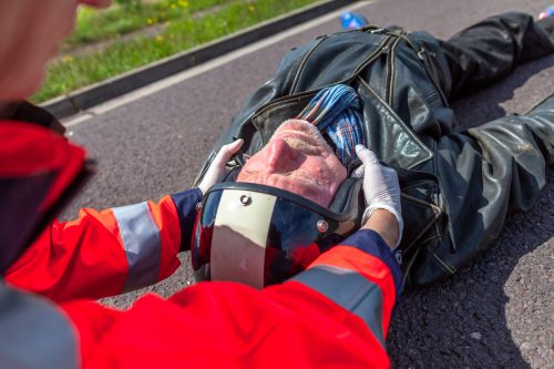 paramedic removes an helmet from an injured biker