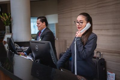 Hotel front desk receptionists, one is taking a call