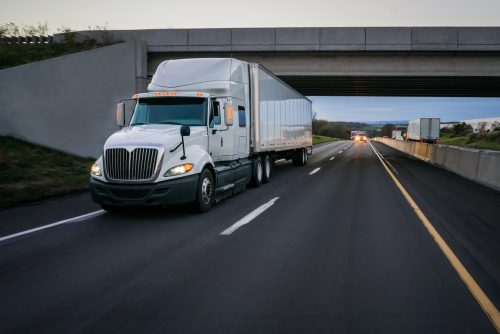 semi tractor trailer driving on the highway in the evening