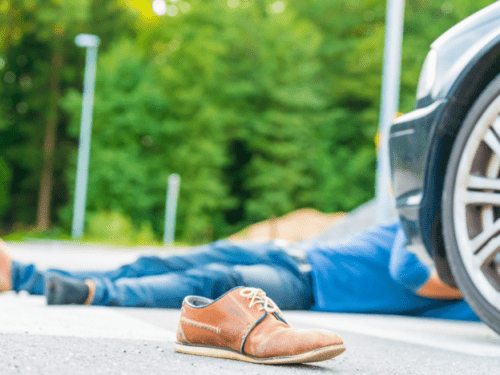 man laying in the road after a car accident