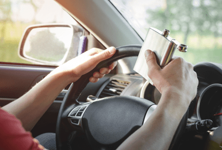 man holding a flask while driving