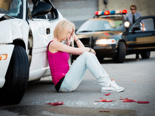 woman leaning on a car after an accident