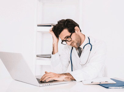 doctor sitting at a laptop scratching his head